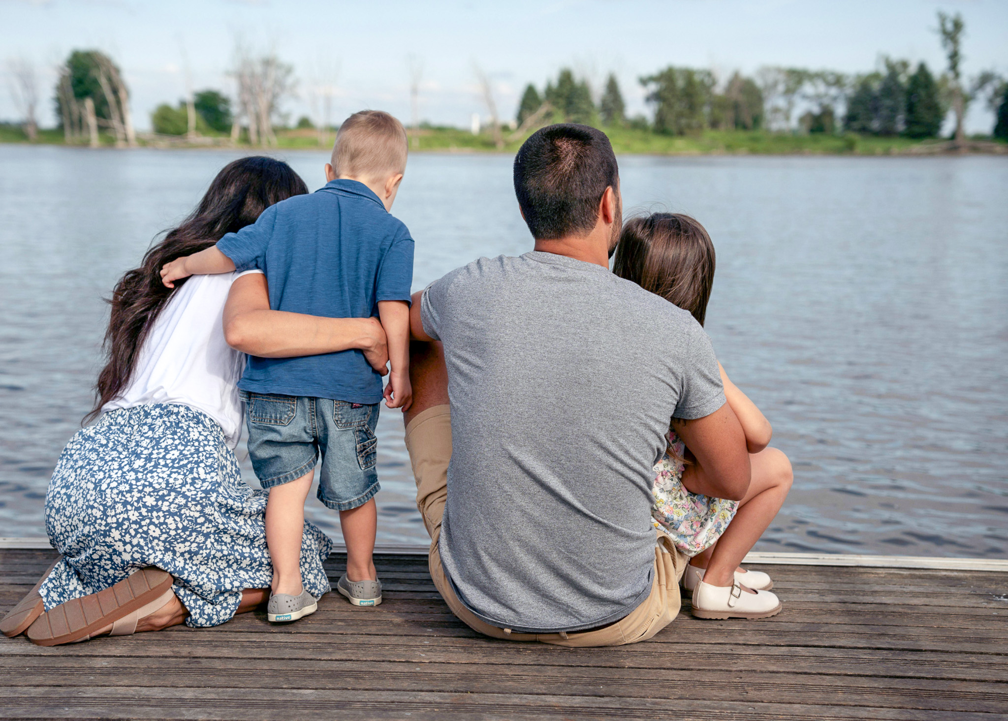 A family of four sit facing a lake on a respite break