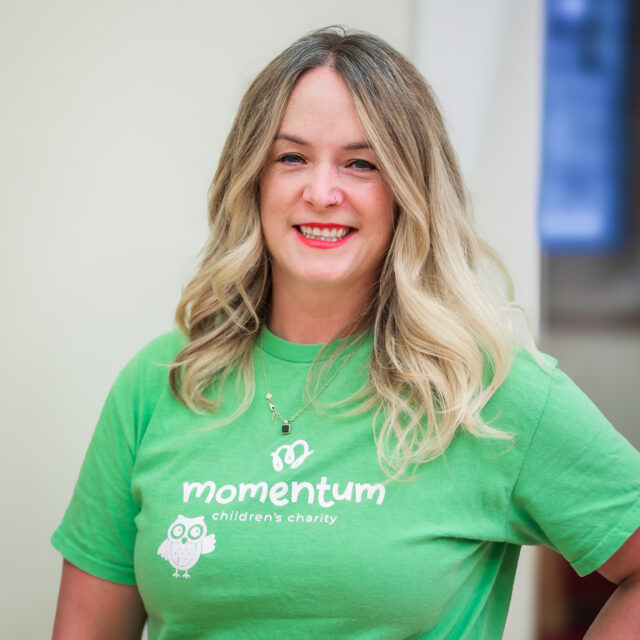 Staff headshot of Momentum Children’s Charity’s Director of Fundraising and Engagement, smiling at the camera in a green charity-branded T-shirt.