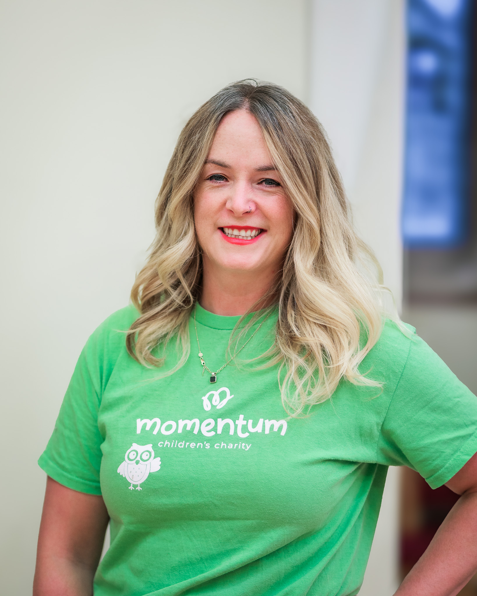 Staff headshot of Momentum Children’s Charity’s Director of Fundraising and Engagement, smiling at the camera in a green charity-branded T-shirt.
