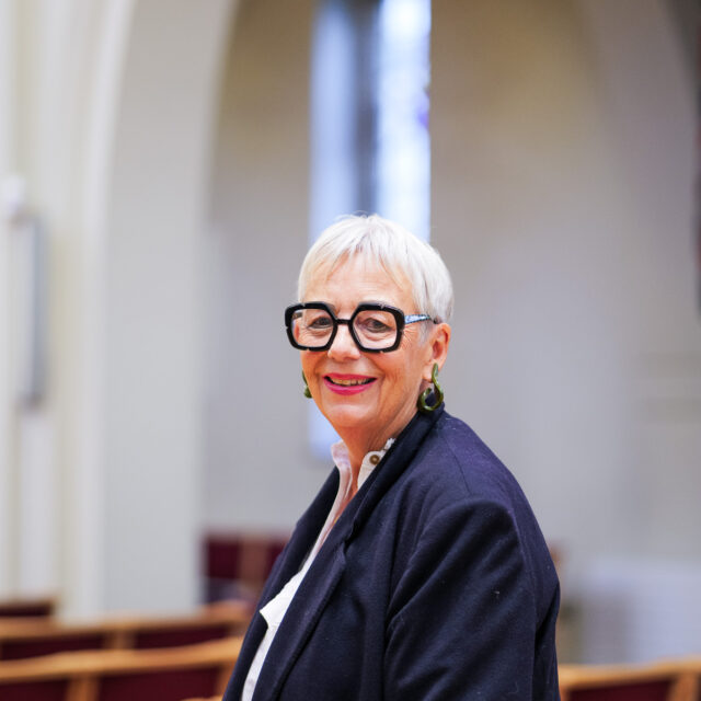 Portrait of Bianca Effemey OBE, founder and trustee of Momentum Children’s Charity, smiling in a navy blazer and white blouse at a church venue.