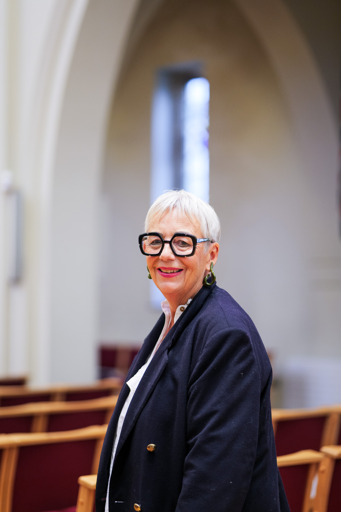 Portrait of Bianca Effemey OBE, founder and trustee of Momentum Children’s Charity, smiling in a navy blazer and white blouse at a church venue.