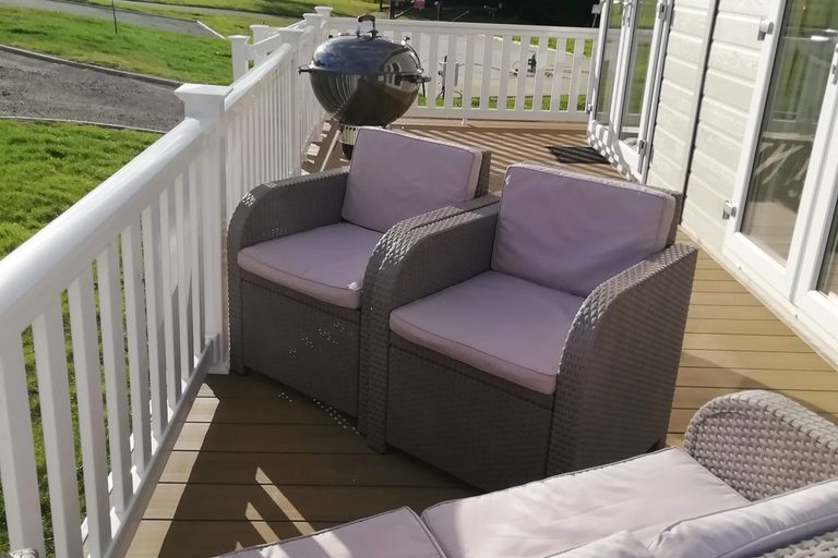 Private veranda with outdoor seating at Mo's Keep respite lodge, Shorefield Country Park"