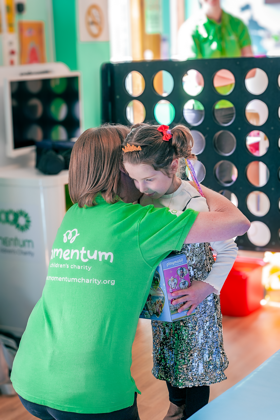 A Family Support Worker hugging a supported child at hospital after giving them a gift.
