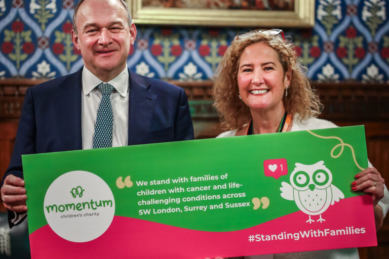 Momentum's CEO and MP Ed Davey standing together with a Momentum sign at a Houses of Parliament event.