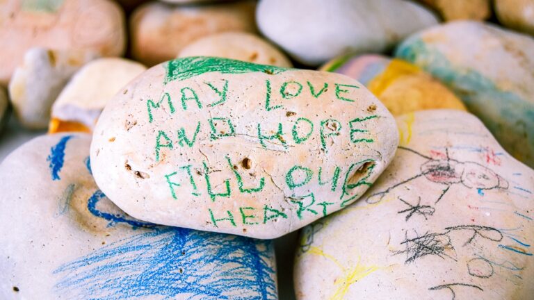 A painted pebble reading, may love and hope fill our hearts.