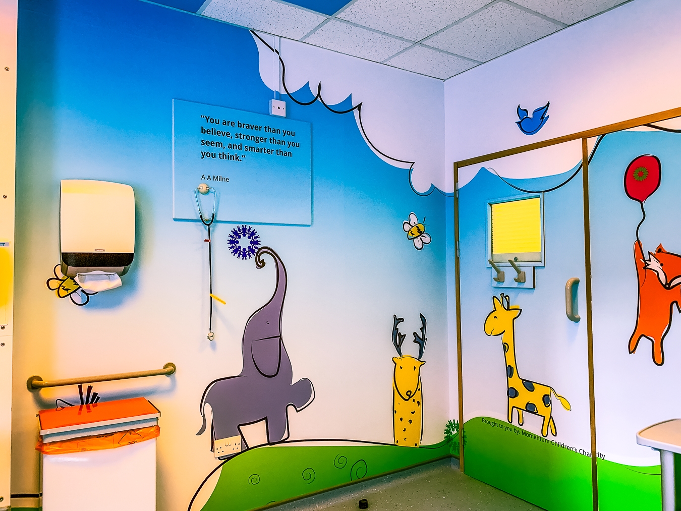 A hospital room decorated with animal designs and a Winnie the Pooh quote on the wall.