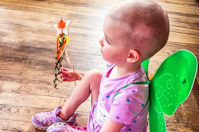 A supported child wearing green fairy wings.