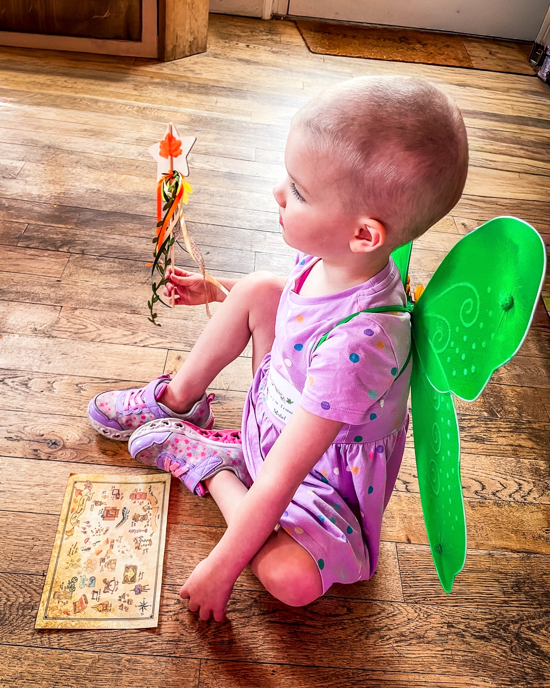 A supported child wearing green fairy wings.