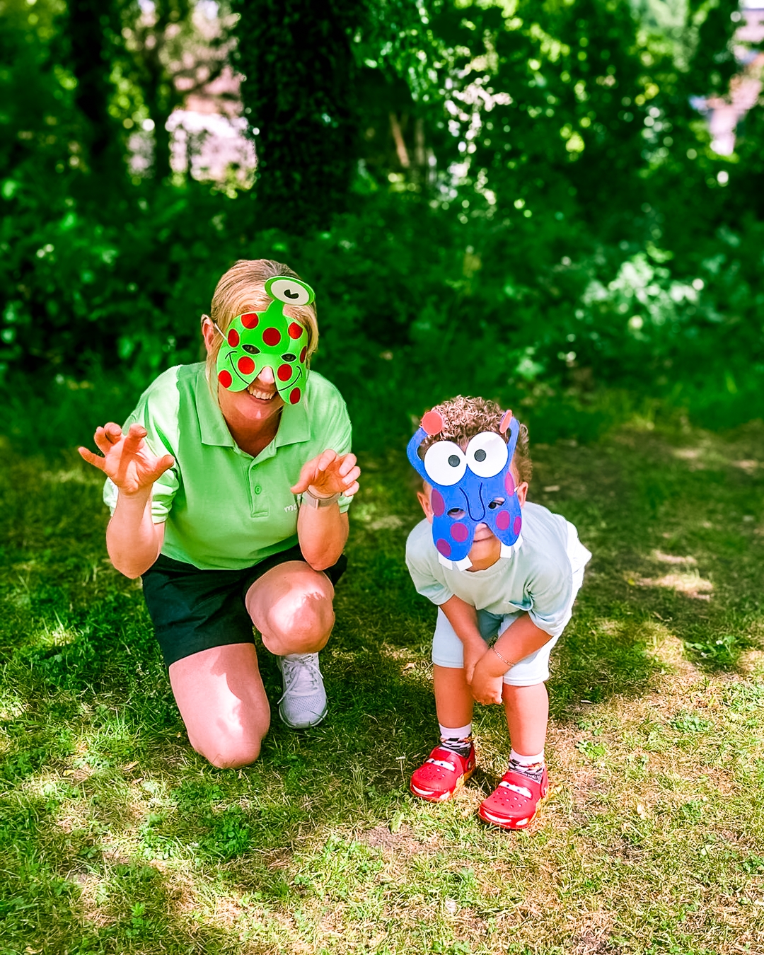 A supported child and Family Support Worker wearing monster masks, playfully holding their hands up to the camera at a Momentum family event day.