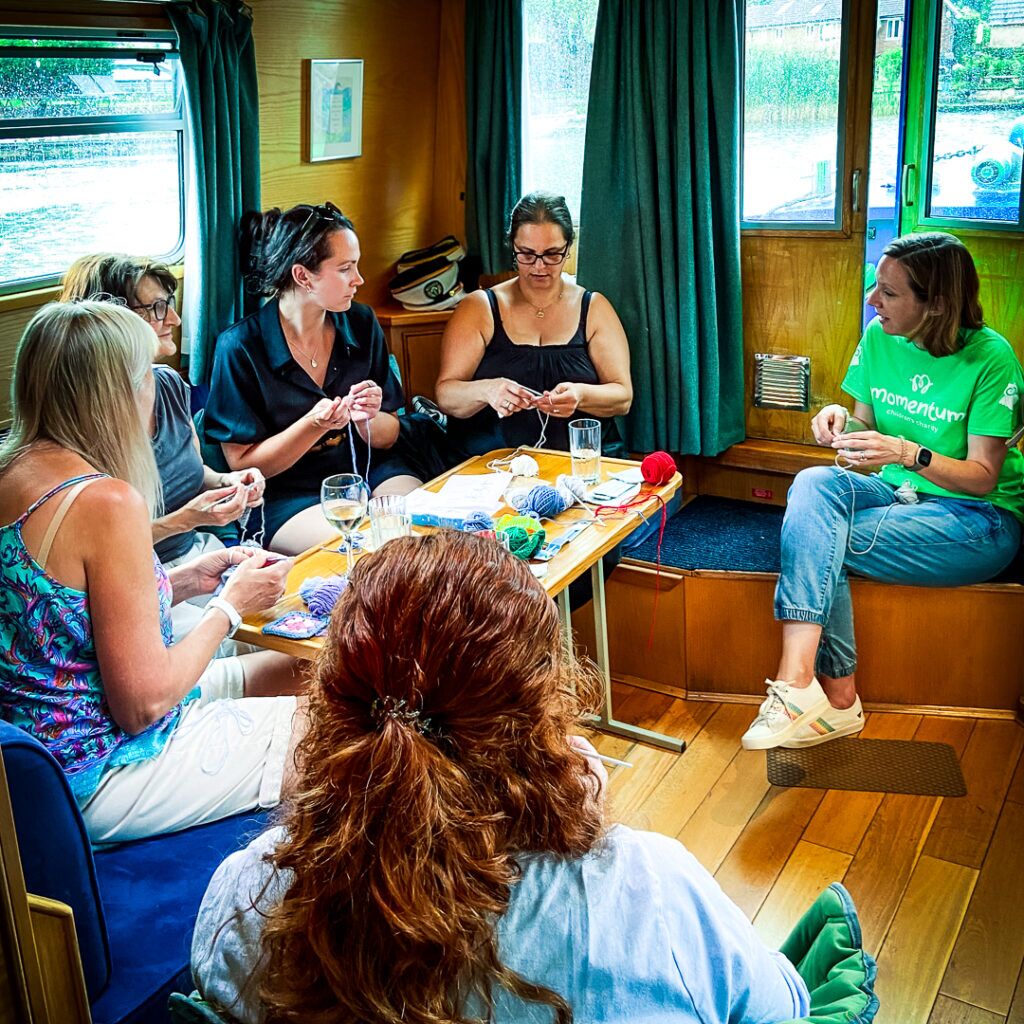 Mothers supported through Momentum's Echoes programme sitting on the Momentum boat doing crafts together.