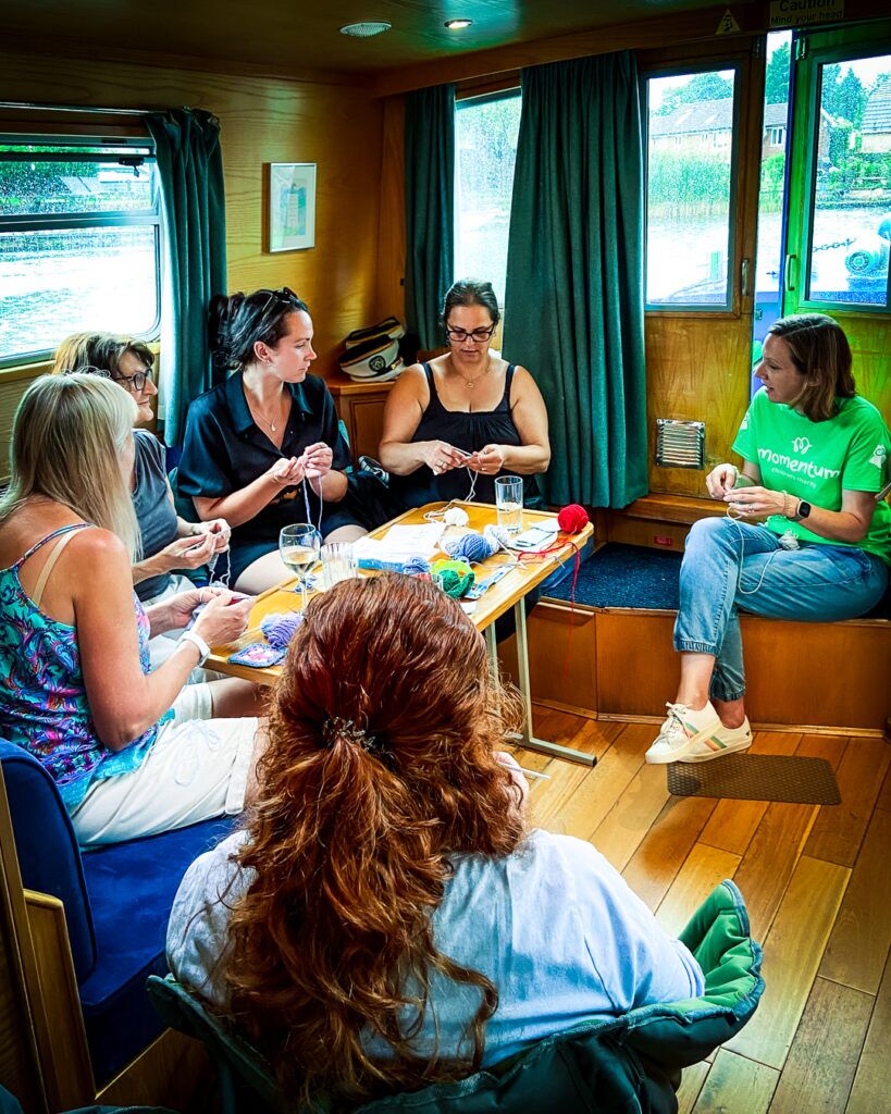 Mothers supported through Momentum's Echoes programme sitting on the Momentum boat doing crafts together.