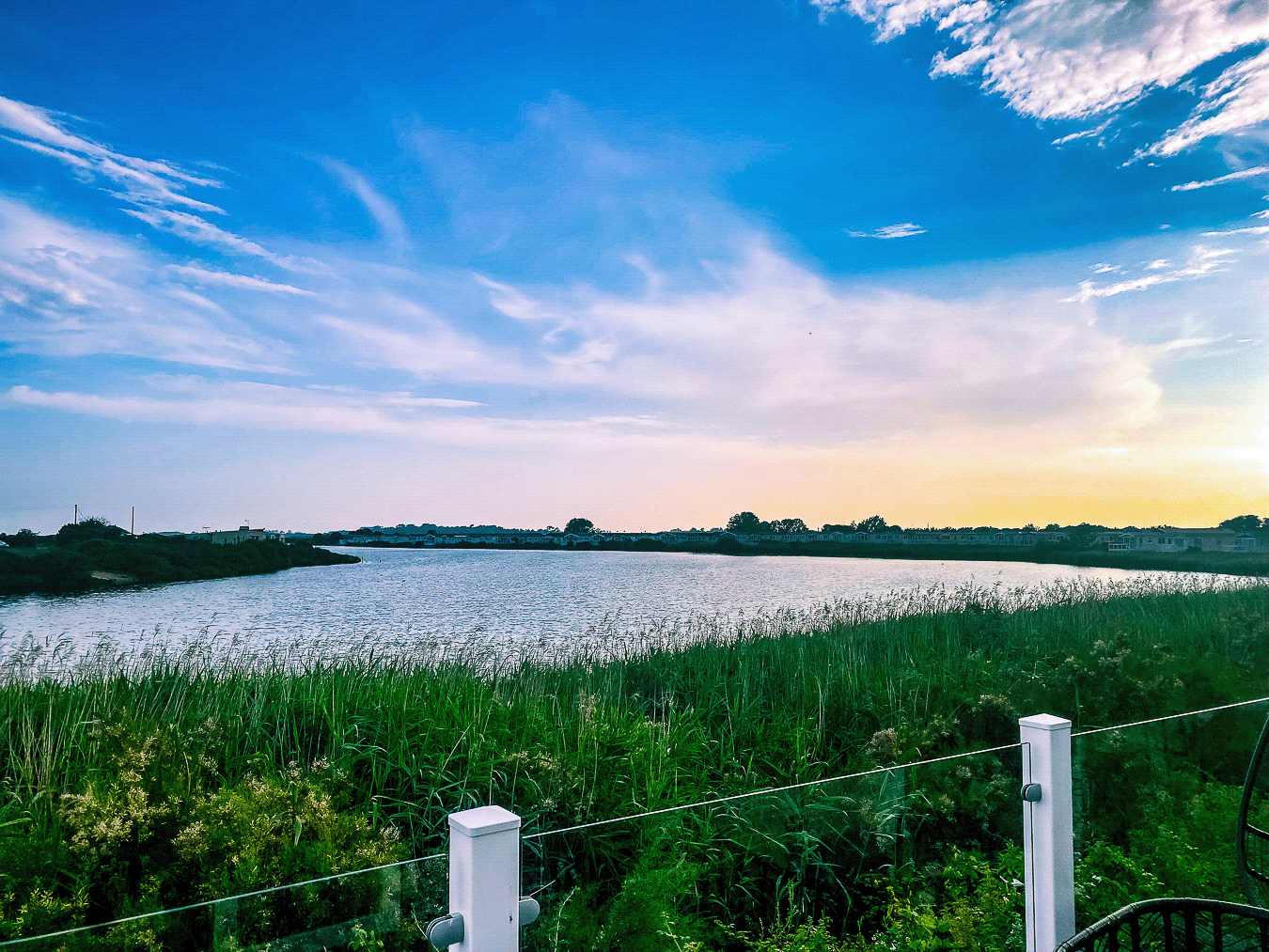 Sunset over the peaceful lagoon, viewed from the balcony decking of Momentum’s respite cabin at Church Farm Holiday Village.