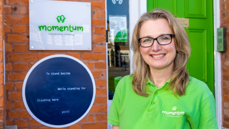 A social worker standing with a plaque celebrating her work at Momentum Children's Charity.