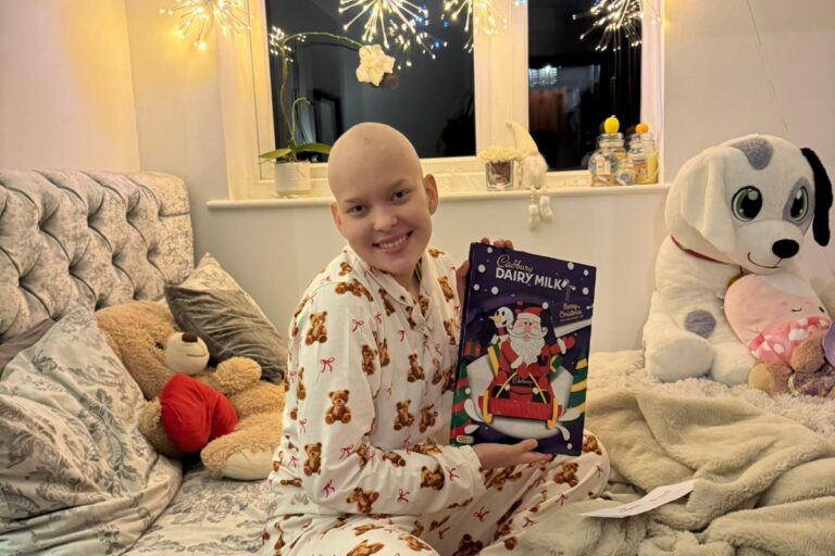 Momentum supported child in Christmas PJs receives an advent calendar