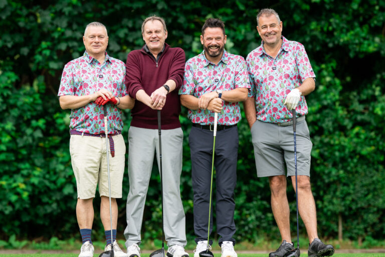 TV's Phil Glennister poses with three men with golf clubs and matching shirts.