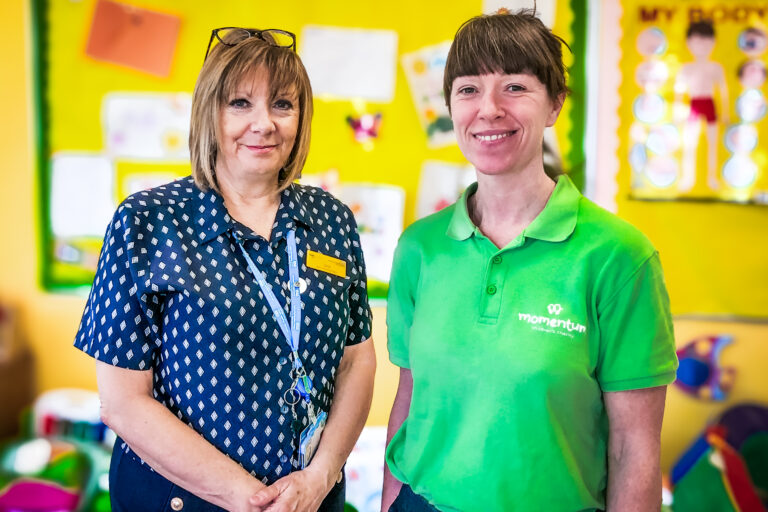 A Momentum family support worker stands in their green polo shirt alongside a member of staff at a partner hospital in Sussex.