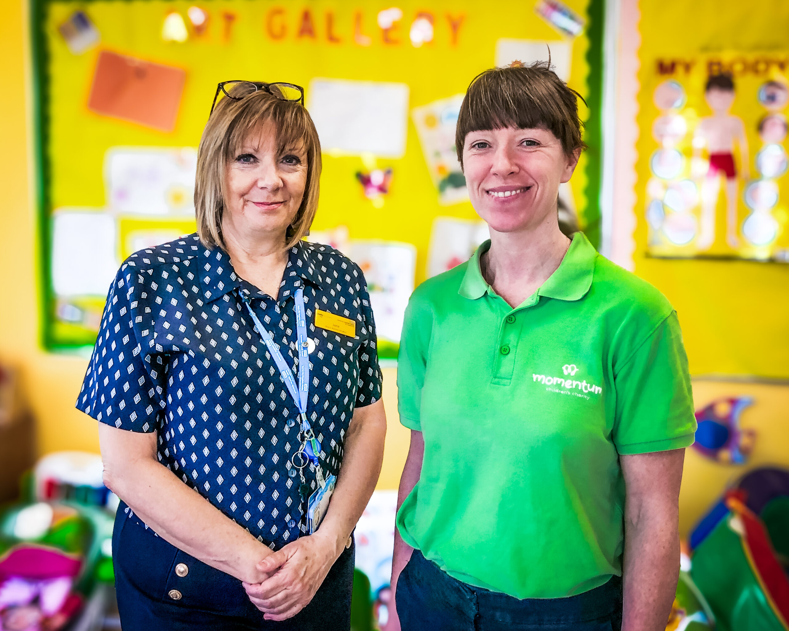 A Momentum family support worker stands in their green polo shirt alongside a member of staff at a partner hospital in Sussex. 