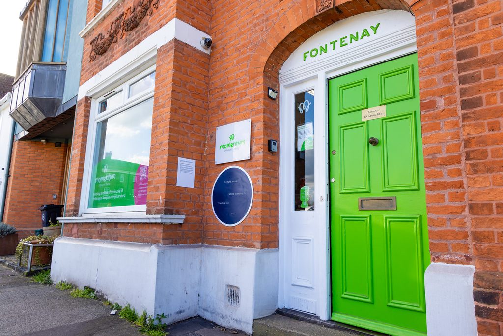 The Momentum Children's Charity office building, with red bricks and a green front door.
