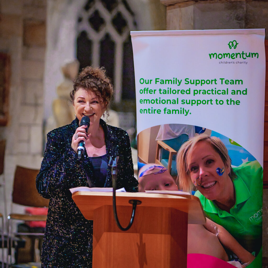 A singer at a christmas concert infront of a momentum branded banner