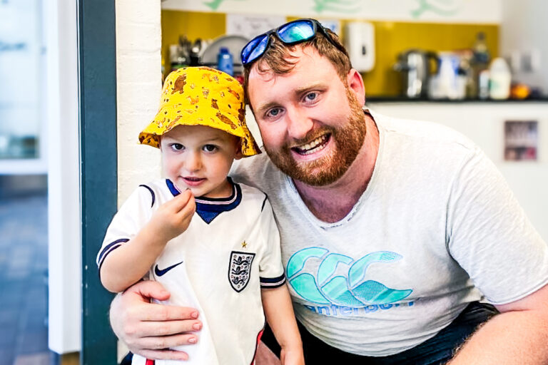 A father and his young son in a yellow bucket hat smile as they enjoy a day at London Zoo