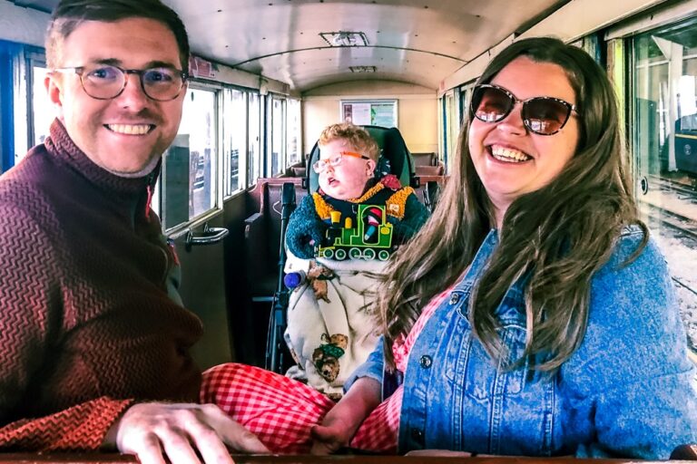 A mother and father smiling with their son on board a steam train