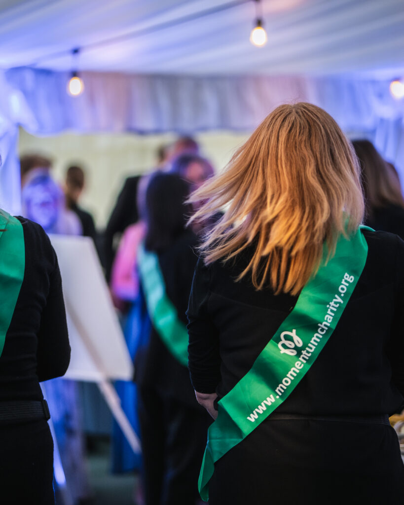 Momentum volunteers wearing green sashes at a fundraising event.