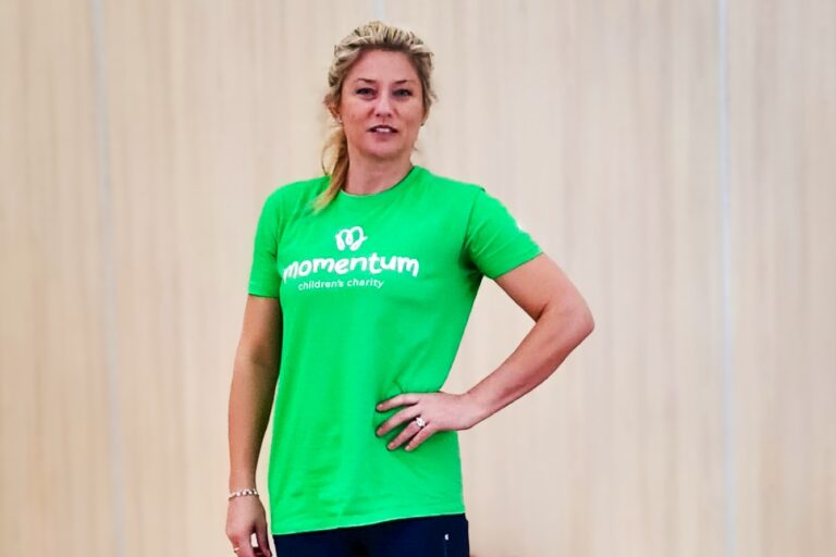 Yoga teacher poses on her yoga mat wearing a Momentum Children's Charity t-shirt.