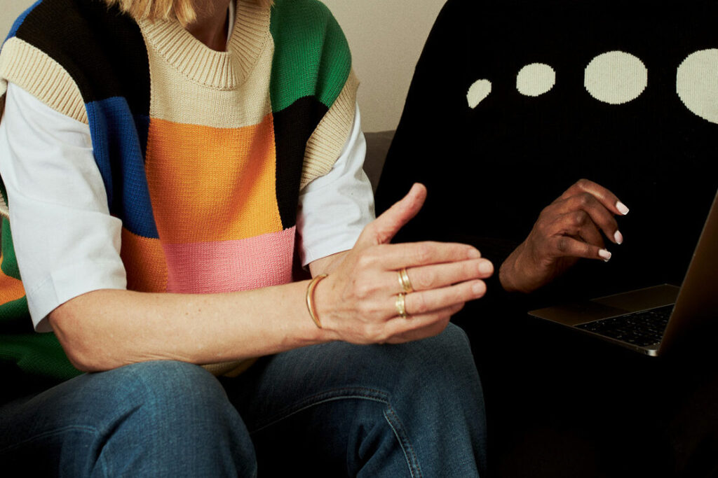 Two women sat together on a sofa, one holding a laptop.