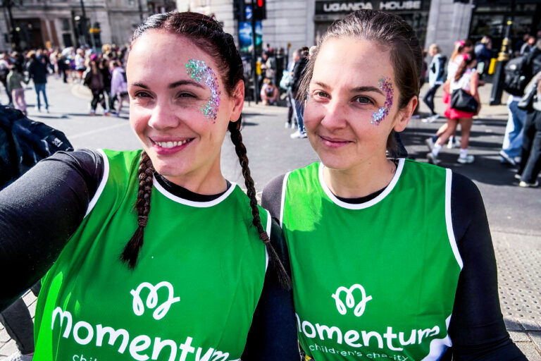 Two female runners with brown hair wear their Momentum running vests at the London Landmarks Half Marathon