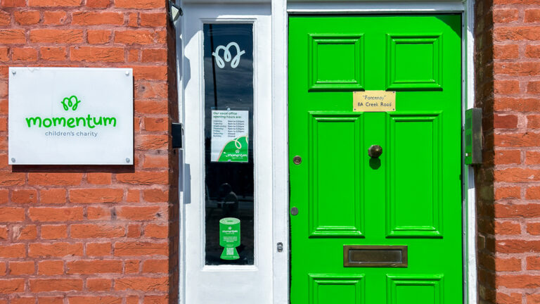 Front green door at Momentum children's charity office with the Momentum Logo beside