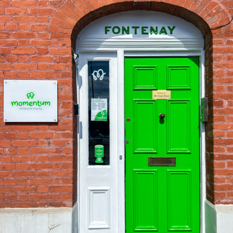 Front green door at Momentum children's charity office with the Momentum Logo beside