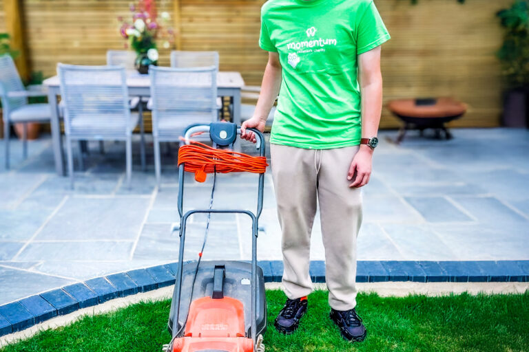A Momentum Young Ambassador poses with his lawn mower following his 'Move for Momentum 2025' mowing challenge.