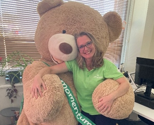 Momentum's Social Worker poses together with a huge teddy bear.