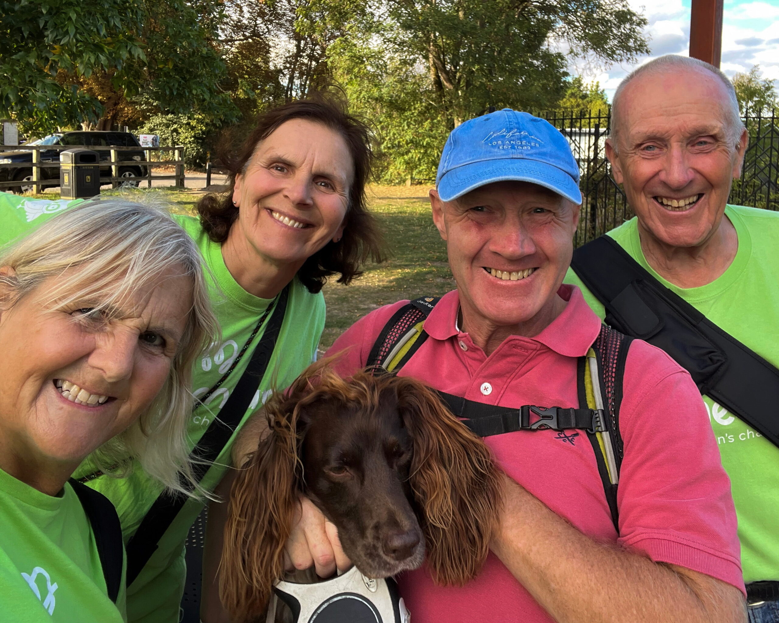 Two women and two men wearing Momentum t-shirts pose with a dog.