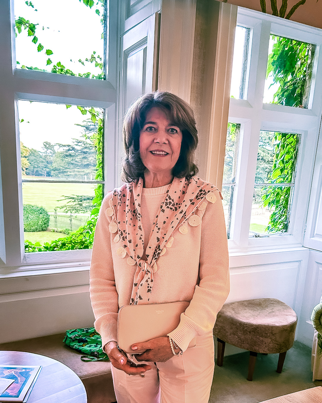 A woman smiles in front of a window.