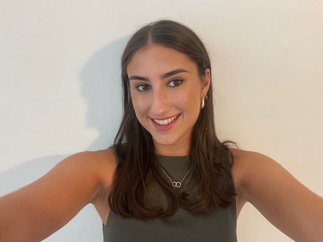 A girl in a black top and long dark hair smiles for the camera.