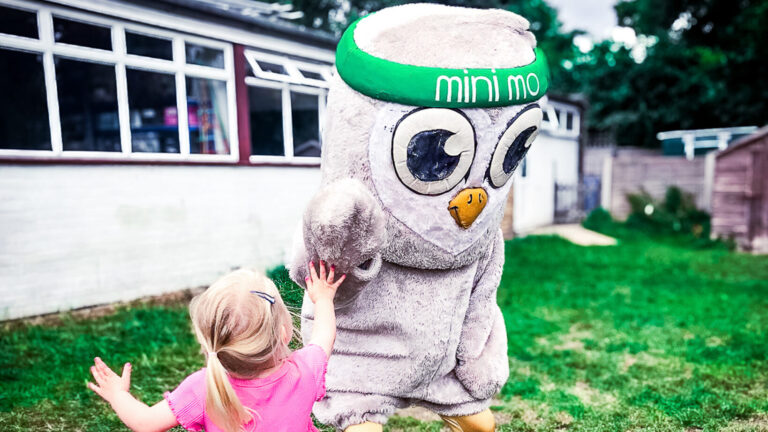 A child high-fiving Mo the mascot in a playground during Move for Momentum.