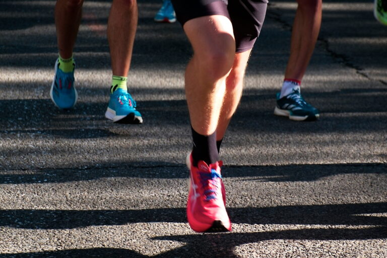 Runners taking part in a South London half marathon, wearing colourful running shoes on a sunlit road. Running event supporting charity fundraising and fitness challenges in South London.