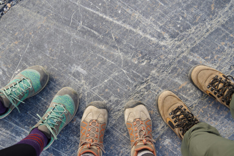 A group of walking boots and trainers viewed from above, representing participants preparing for a charity winter walking challenge.
