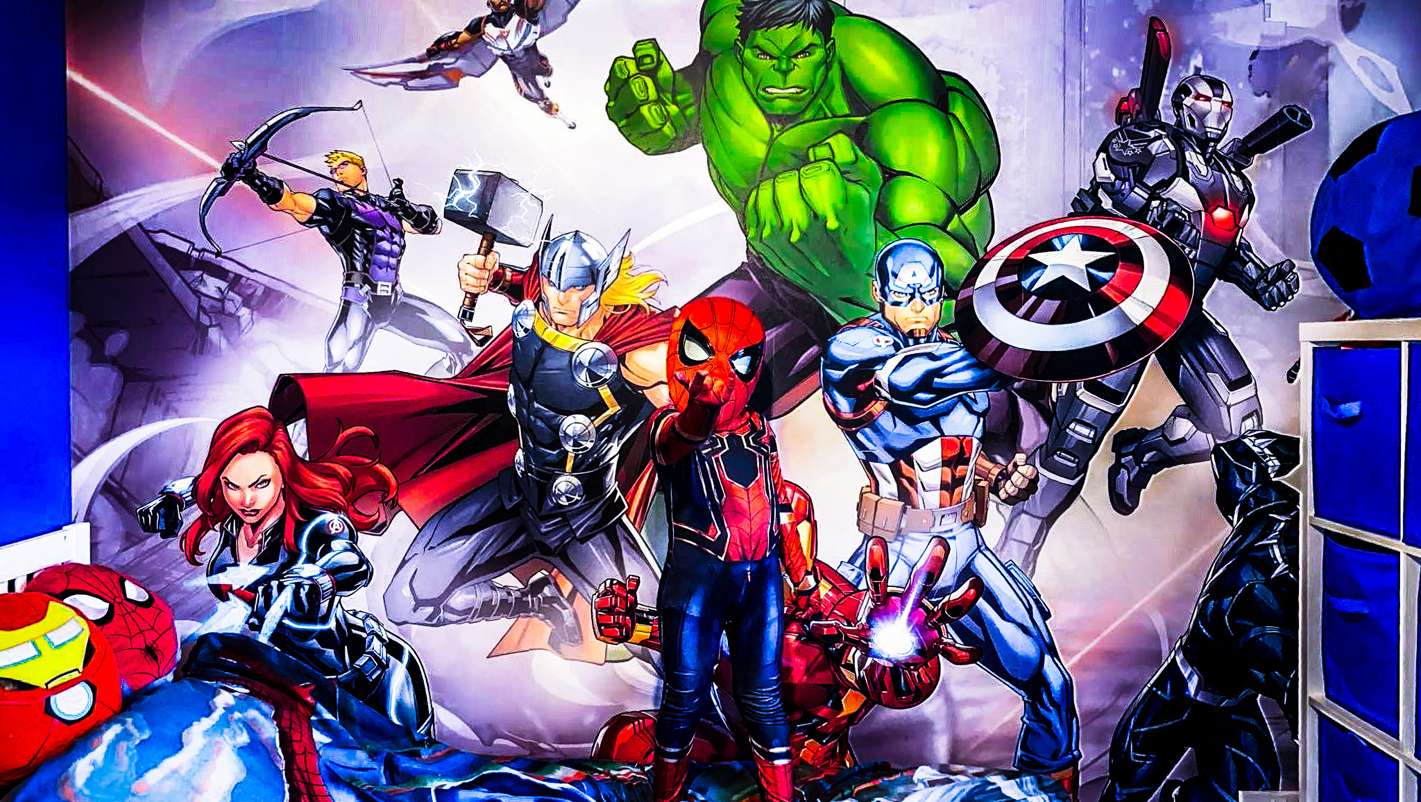 A boy dressed up as Spiderman does the Spiderman fingers stood in his newly made-over Marvel-themed bedroom.