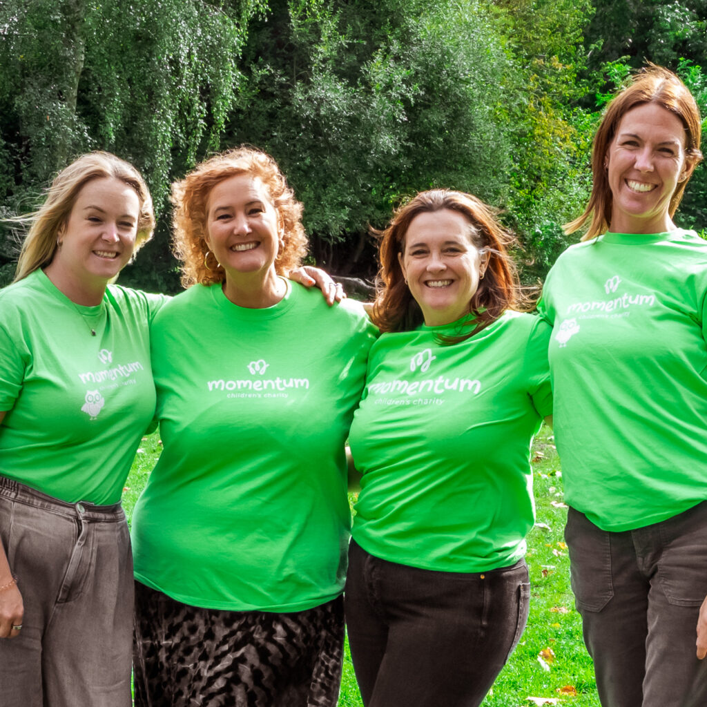 A group of Momentum Senior Management Team standing in the park in a group wearing Momentum Tshirts and smiling to the camera